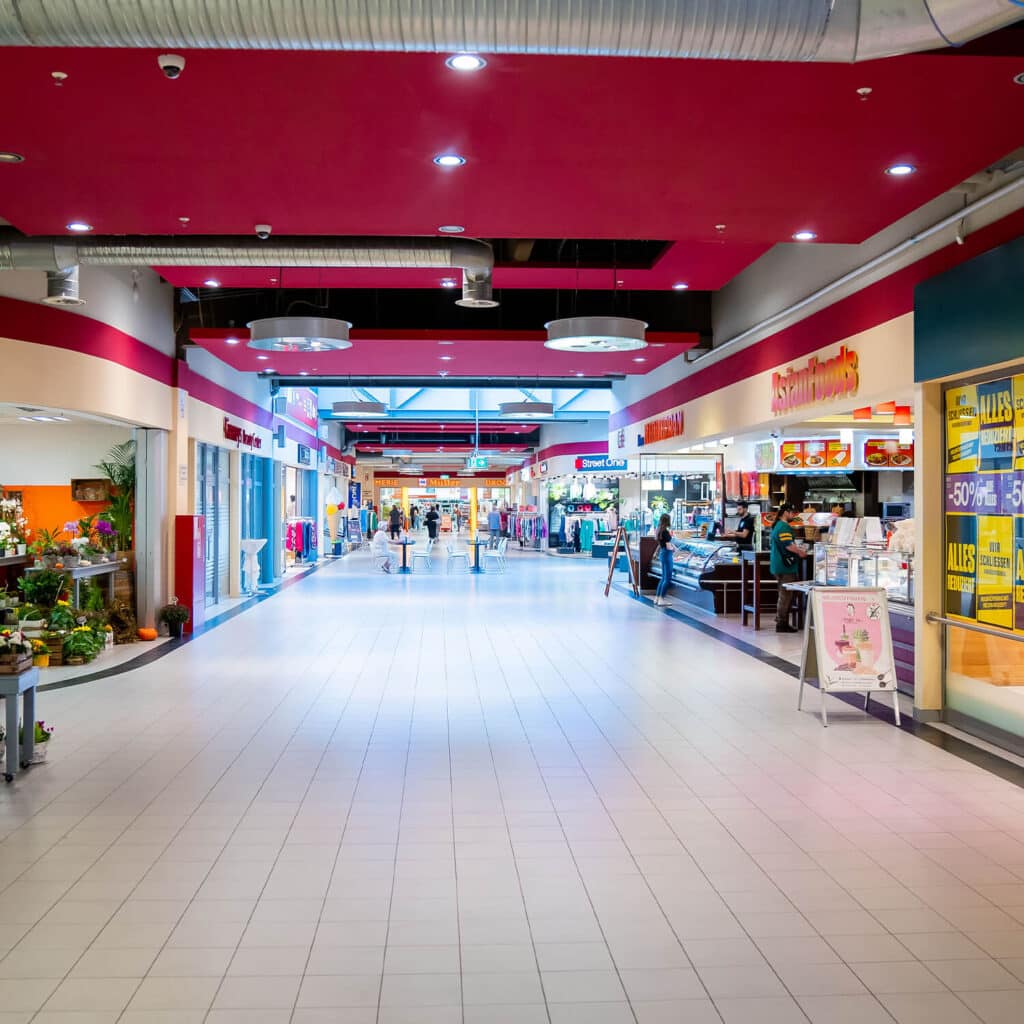 Weitläufige Einkaufspassage mit hellen Fliesen und mehreren Geschäften