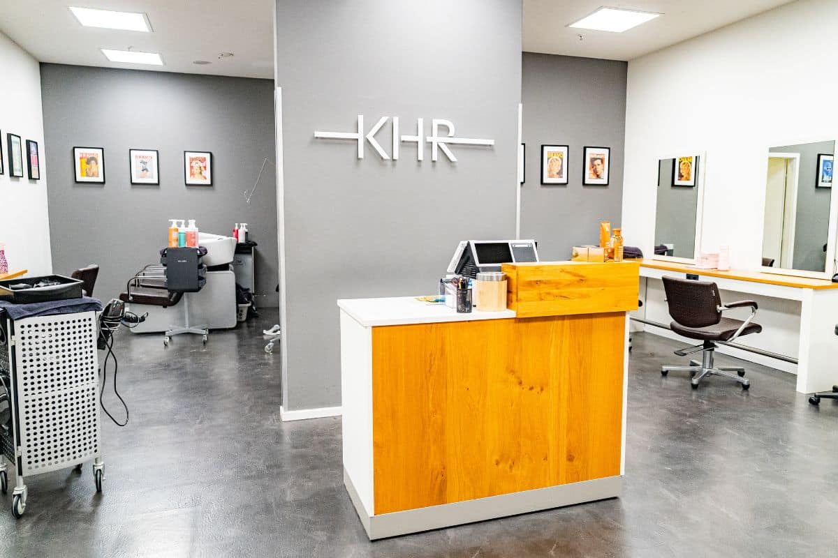 Moderner KHR-Friseur-Innenbereich mit heller Empfangstheke aus Holz und weißen Elementen