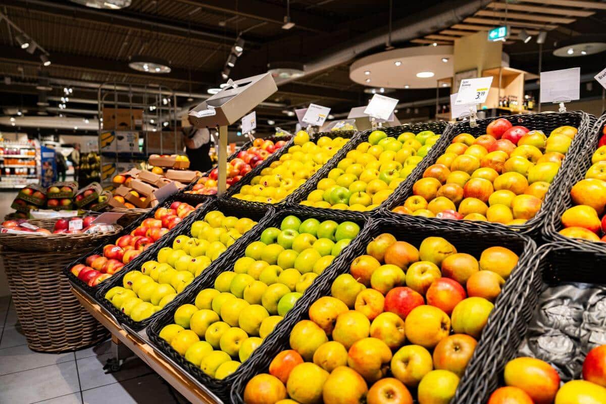 Frischobstabteilung mit ordentlich sortierten Körben verschiedener Apfelsorten