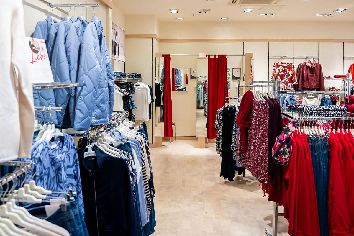 Innenansicht mit mehreren Kleiderstangen und Umkleidekabinen mit roten Vorhängen