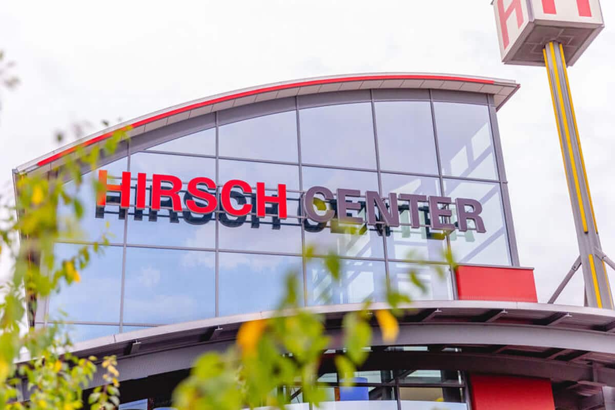 Glasfassade des Hirsch Centers und teilweise sichtbaren grünen Blättern im Vordergrund